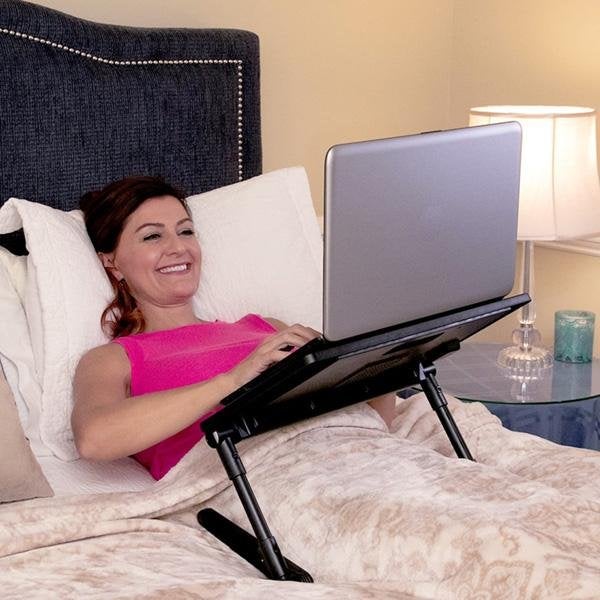 Woman laying in bed using laptop that is resting on an AirSpace over her lap