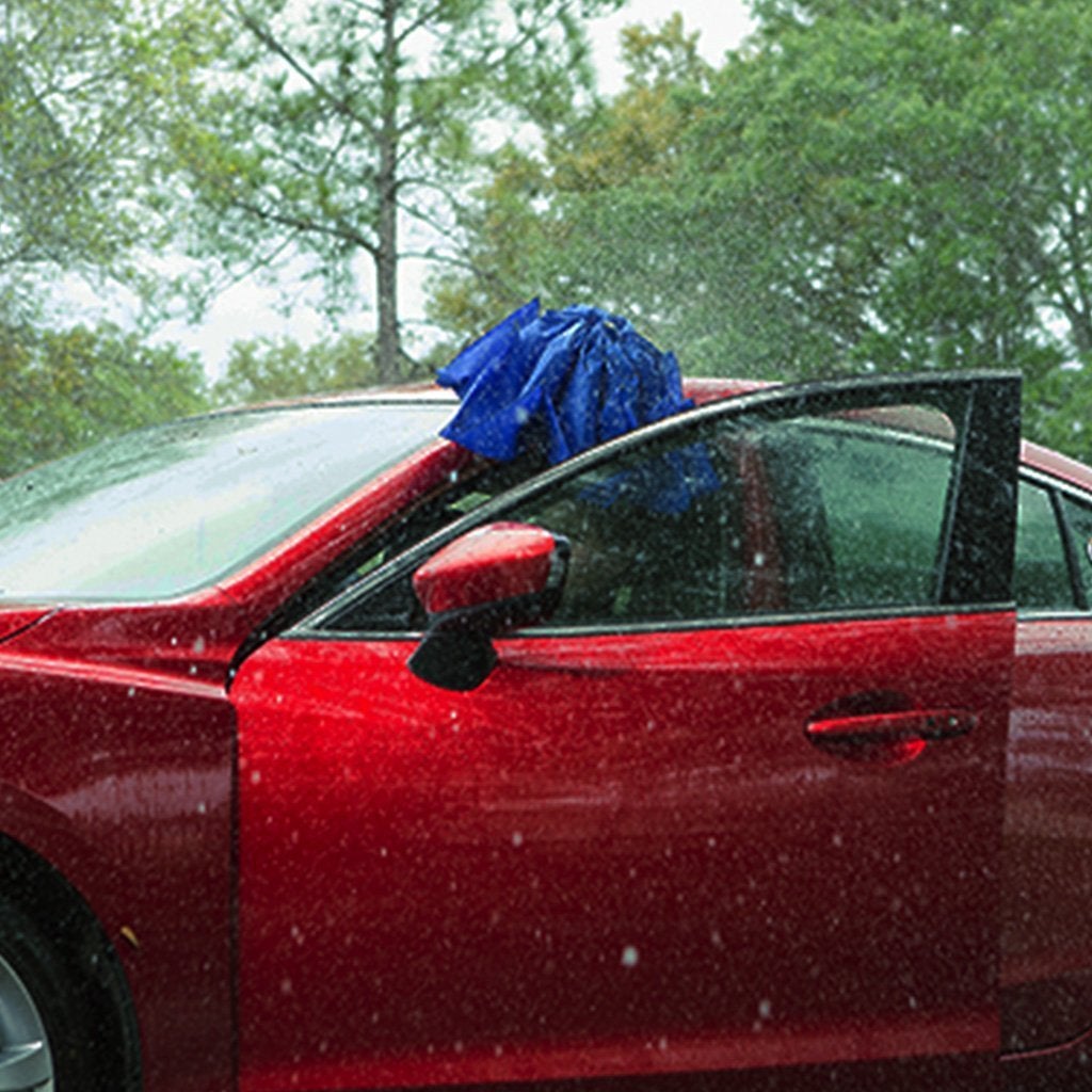 Woman getting into car in rain holding Backward Brella to cover her head