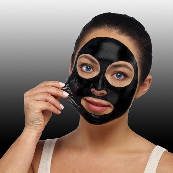 Woman peeling charcoal face mask off of face