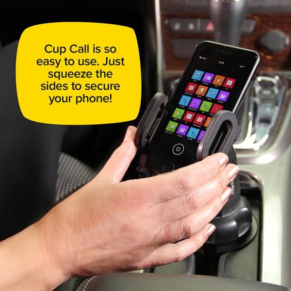 Smart phone in a Cup Call that is in a cup holder inside a car with a person squeezing the sides. Text says Cup Call is so easy to use. Just squeeze the sides to secure your phone