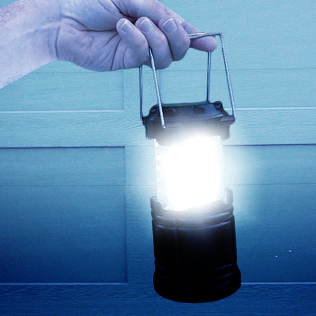 Close up of man holding an Atomic Beam Lantern with the light on