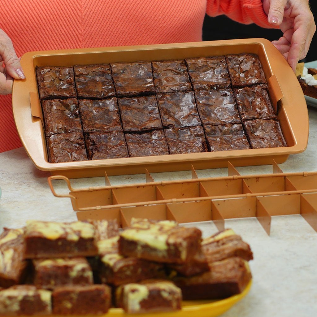 Woman holding up a Red Copper Brownie Bonanza Pan with brownies inside
